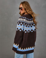 Brown Fair Isle cardigan with blue and cream patterned yoke and zigzag hem, worn with light wash jeans and aviator sunglasses
