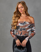 Woman wearing brown floral mesh off-shoulder long-sleeve bodysuit with black jeans, holding woven leather clutch