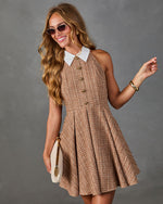 Woman wearing brown tweed halter mini dress with white collar, gold buttons, sunglasses, and cream clutch bag