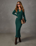 Woman in a green ribbed knit long-sleeve midi dress with henley neckline, brown suede heeled boots and a faux fur clutch