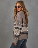 Woman in a taupe Fair Isle knit sweater with black and cream patterns, styled with gray wide-leg jeans and gold sunglasses