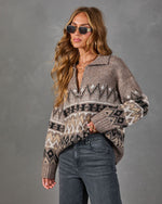 Woman wearing a taupe Fair Isle zip-up collared sweater with black and cream patterns, styled with gray jeans and sunglasses