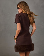 Brown short-sleeve wool mini dress with faux fur hem, worn with gold bangles and tortoiseshell sunglasses, back view