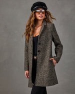 Woman wearing a herringbone tweed wool coat with black top, pants, suede newsboy cap and tinted aviator sunglasses