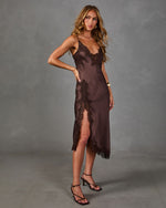Woman wearing a brown satin midi slip dress with lace trim and thigh-high slit, styled with black strappy heeled sandals