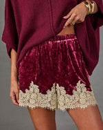 Burgundy crushed velvet shorts with cream lace trim and elastic waist, styled with an oversized knit sweater and gold bangles