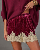 Burgundy crushed velvet shorts with cream lace trim and elastic waist, styled with an oversized knit sweater and gold bangles