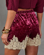 Burgundy crushed velvet shorts with cream lace trim, shown from behind with a matching knit crop top and gold bangles