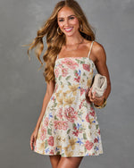 Women's ivory floral mini dress with spaghetti straps, A-line skirt, pink roses print, styled with gold hoops and woven clutch