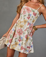 Women's white floral mini dress with spaghetti straps, pink roses print, A-line skirt, styled with gold bangles and woven bag