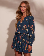Navy blue floral mini dress with long sleeves, V-neckline, and tiered skirt worn by a woman