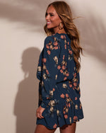 Navy floral long-sleeve mini dress with ruffle hem, worn by woman with wavy auburn hair and gold hoop earrings