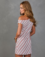Woman modeling off-shoulder striped mini dress in white and mauve diagonal print with gold bangle bracelet