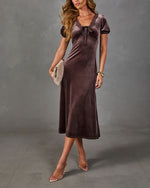 Brown velvet midi dress with lace-trim neckline, satin bow and puff sleeves, styled with clear heels and woven clutch
