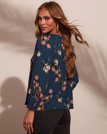 Navy floral blouse with long sleeves and pink cream flowers, worn by woman with auburn hair, styled with dark jeans