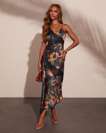 Floral satin slip midi dress with black lace trim, deep teal background, worn with clear heels and tan mini bag
