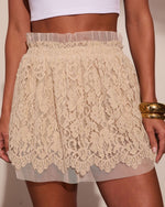 Cream floral lace mini skirt with scalloped hem and tulle waistband, paired with white crop top and gold cuff bracelet