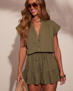 Woman wearing olive green cotton gauze romper with ruffle sleeves, V-neck, drawstring waist, and tiered skirt shorts