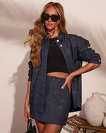 Woman wearing embellished denim co-ord set with gold stud details, black crop top, oversized jacket and mini skirt, sunglasses