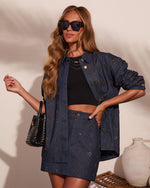 Woman wearing embellished denim co-ord set with gold studs, black crop top, oversized jacket, mini skirt, and woven bag