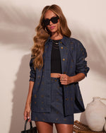 Woman wearing embellished dark denim shacket and mini skirt set with gold stud details, black crop top, and oversized sunglasses