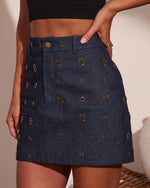 Dark navy denim mini skirt with gold floral stud embellishments and diamond quilted stitching, paired with black crop top