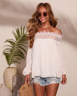 White off-shoulder lace crochet boho blouse with long sleeves, styled with denim cutoff shorts and woven bag, summer fashion