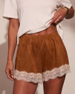 Brown suede mini shorts with cream lace trim hem, elastic waistband, styled with white tee and gold jewelry