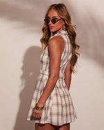 Woman in cream plaid sleeveless mini dress with collar, gold bangles, hoop earrings, and retro cat-eye sunglasses