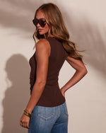 Woman wearing fitted dark brown sleeveless tank top with ruched side detail, blue jeans, gold bangles, and oversized sunglasses