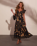 Black floral maxi dress with gold roses, tiered ruffles, lace-up bodice, modeled with strappy heels and woven clutch