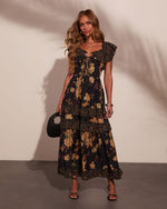 Black floral maxi dress with ruffle tiers and lace-up bodice, styled with black strappy heels and woven clutch