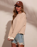Woman wearing cream striped oversized sweatshirt, distressed denim shorts, and brown LA baseball cap, casual streetwear look