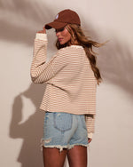Woman wearing cream striped long-sleeve thermal top, distressed denim shorts, and brown corduroy LA baseball cap