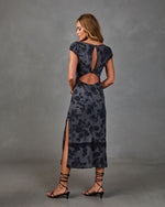 Woman modeling dark floral midi dress with open back cutout, cap sleeves, side slit, and black strappy heels
