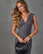 Woman in charcoal linen slip dress with lace V-neckline, holding black woven leather hobo bag, gold jewelry accents