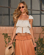 Woman in boho cream lace crop top and rust tiered satin midi skirt with sunglasses and woven bag