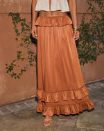 Rust satin maxi skirt with tiered ruffle hem and waist, paired with cream crop top and nude strappy heels