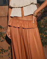 Rust satin maxi skirt with ruffle waist detail, paired with cream lace crop top and gold bangles
