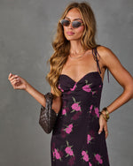 Woman wearing dark floral midi dress with pink roses, tie straps, sunglasses, woven bag, and gold bangles