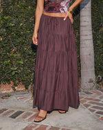 Burgundy tiered maxi skirt with drawstring waist, paired with floral crop top and black strappy sandals, outdoor setting