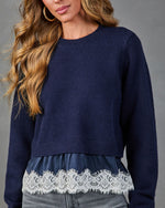 Navy blue cropped knit sweater with white lace hem trim layered over matching satin slip, worn with gray jeans