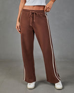 Brown wide-leg track pants with cream side stripes and drawstring waist, paired with white sneakers and crop top