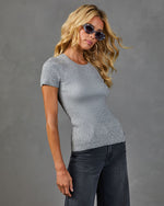 Woman wearing fitted gray ribbed short-sleeve knit top and dark wide-leg jeans with tortoise sunglasses