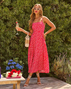 Woman in red floral midi dress, white cat-eye sunglasses, strappy heels, holding champagne at summer garden party