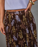 Brown pleated midi skirt with blue and yellow floral print, elastic waistband, styled with lavender knit top and gold cuff