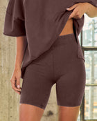 Woman wearing matching dark brown biker shorts and oversized t-shirt set, high waist elastic waistband, fitted athleisure style