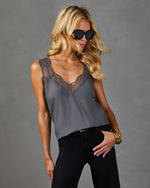 Gray lace-trim satin cami top on blonde model wearing black jeans, gold bangles, layered necklaces, and oversized sunglasses