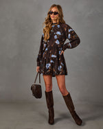 Brown floral mini dress with blue roses, long sleeves and tiered skirt, styled with suede knee-high boots and a quilted bag