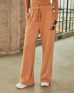 Women's camel wide-leg drawstring pants with elastic waist, worn with white sneakers and matching crop top, street style look
